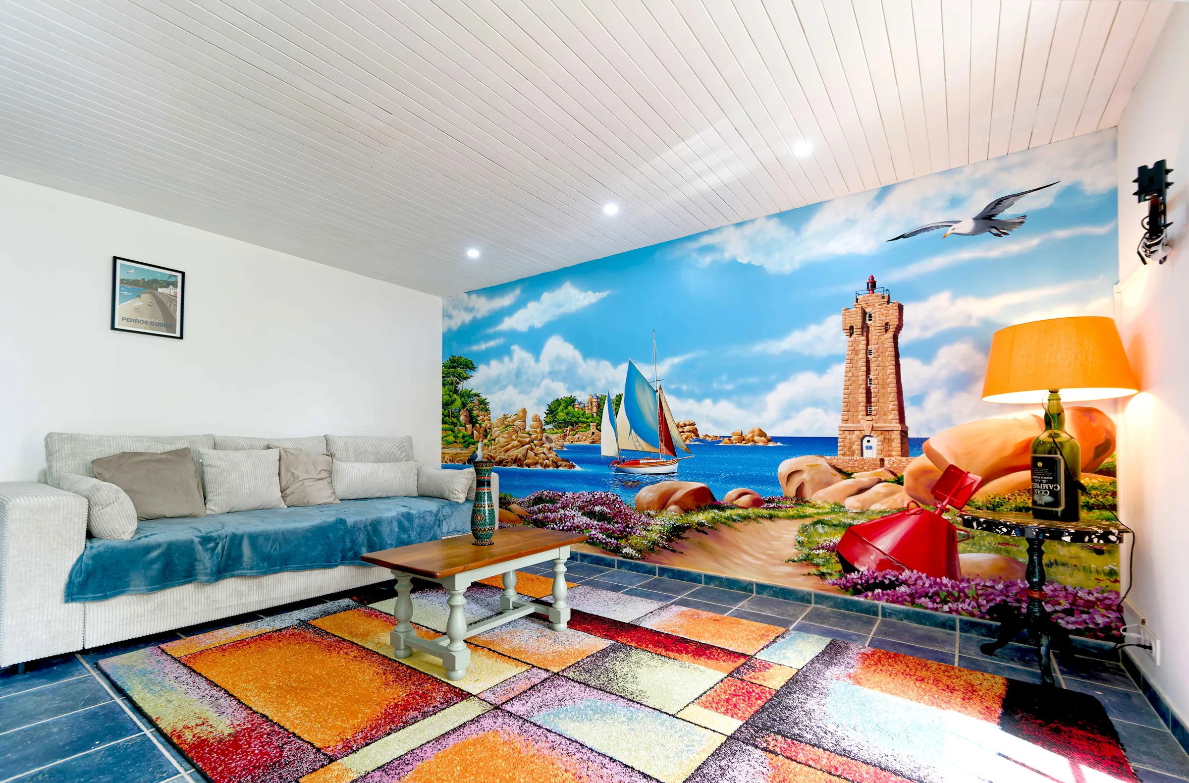 Fresque murale en trompe-l'œil dans un salon de particulier : paysage maritime et vieux gréements sur la côte de granit rose, à Ploumanac'h, réalisée par Gwendal Larher